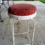 A red stool sitting on top of a cement floor.