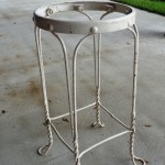 A white metal table with chain legs and a round top.