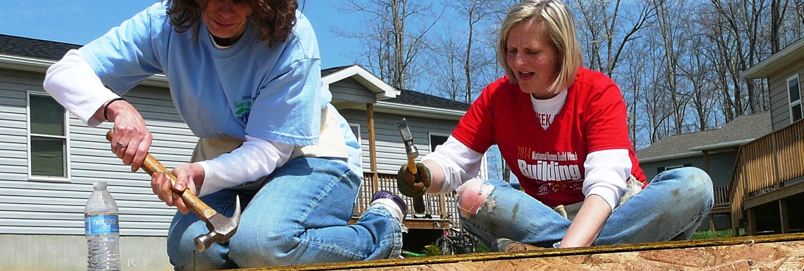 Two women sitting on a deck with scissors in their hands.