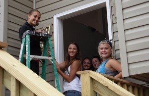 A group of young women standing on the steps to their new home.