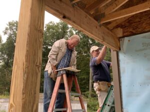 Two men working on a house with some ladders