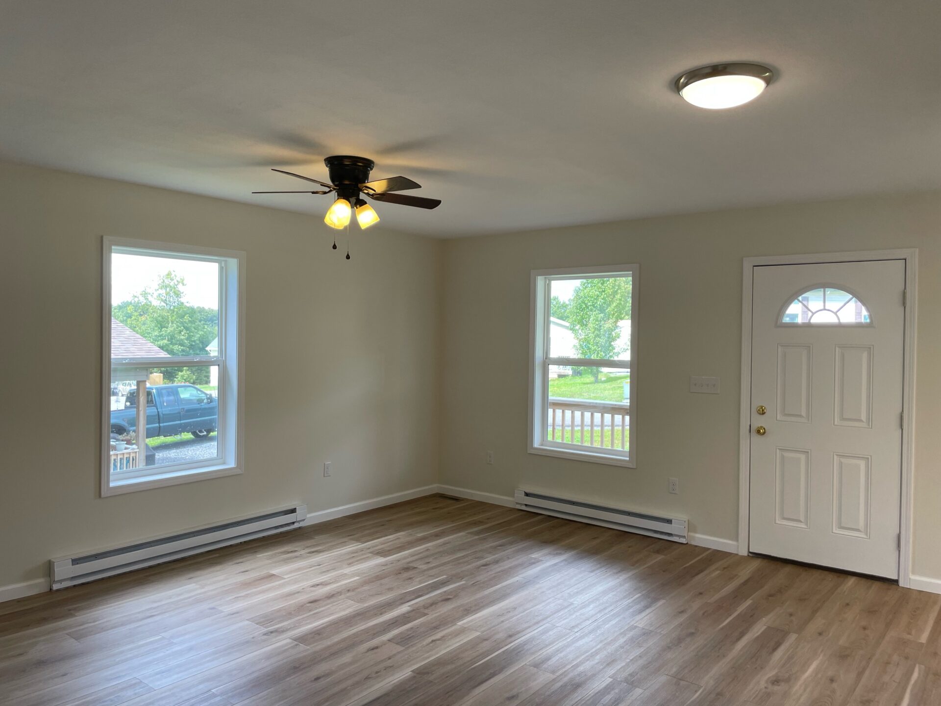 A room with hard wood floors and a ceiling fan.